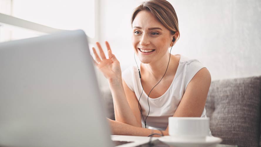 Lady on a webinar, waving at her laptop camera